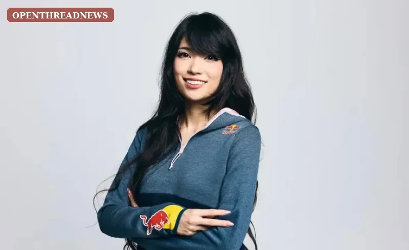 A gamer wearing a headset competing at an esports arena under dramatic red and blue stage lighting, tied to Emiru's Red Bull partnership