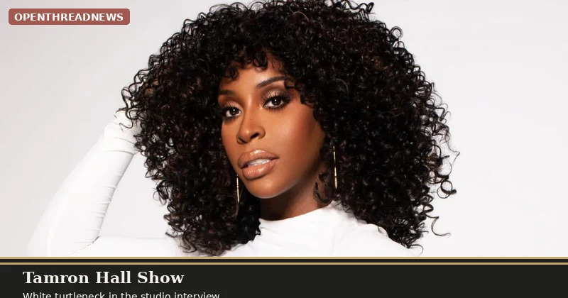 Jackie Aina in a white turtleneck with voluminous curly hair, gold earrings, studio portrait from a Tamron Hall Show appearance